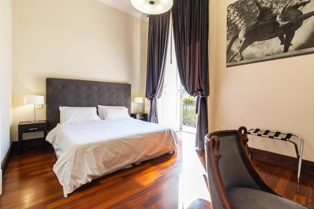 a bedroom with a bed and a chair and a window at Gramsci Suites in Naples