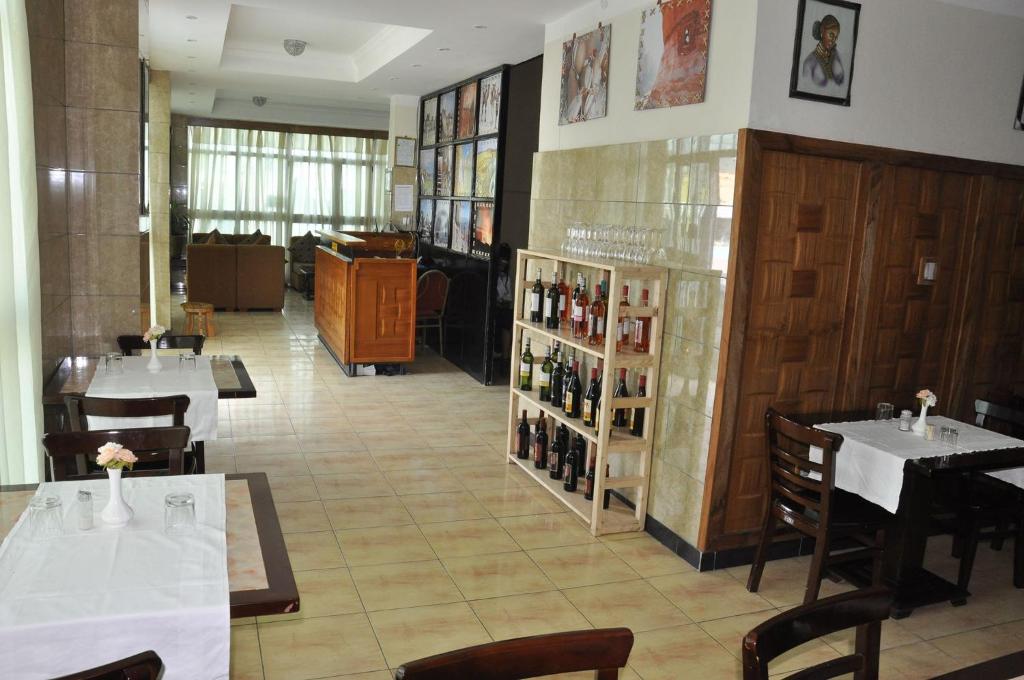 a restaurant with tables and chairs and a room with wine bottles at Mekelle Hotel in Mekʼelē