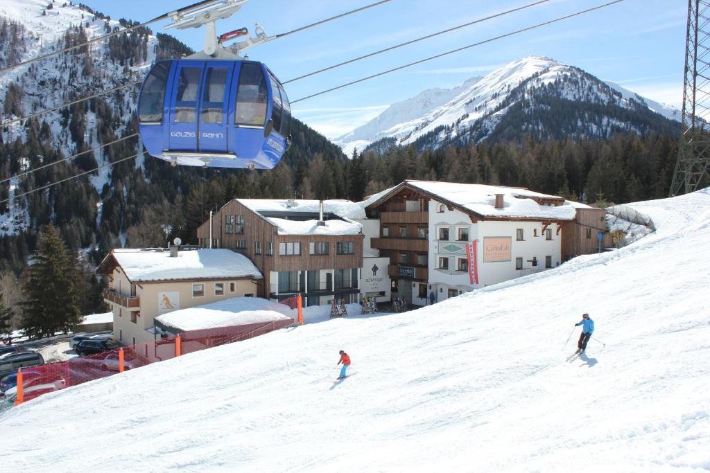 duas pessoas a esquiar numa pista coberta de neve ao lado de um teleférico em Appartement Erich Schweiger em Sankt Anton am Arlberg