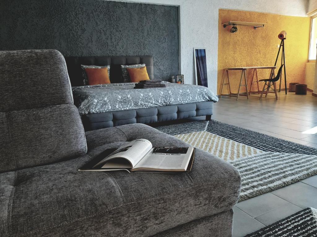Un dormitorio con una cama y un sofá con un libro. en 21 Suites Deluxe Stay Near The Airport, en Markopoulo