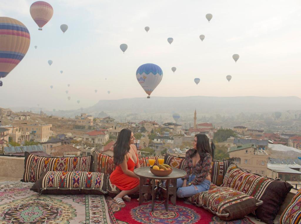 zwei Mädchen, die auf einer Couch sitzen und Heißluftballons gucken in der Unterkunft Alia Cave Hotel in Goreme