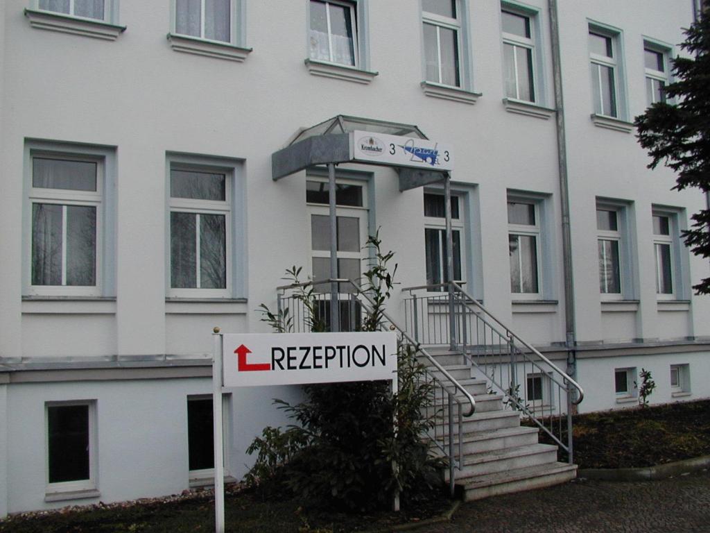 a sign in front of a white building at Apart-Hotel-Pension in Taucha