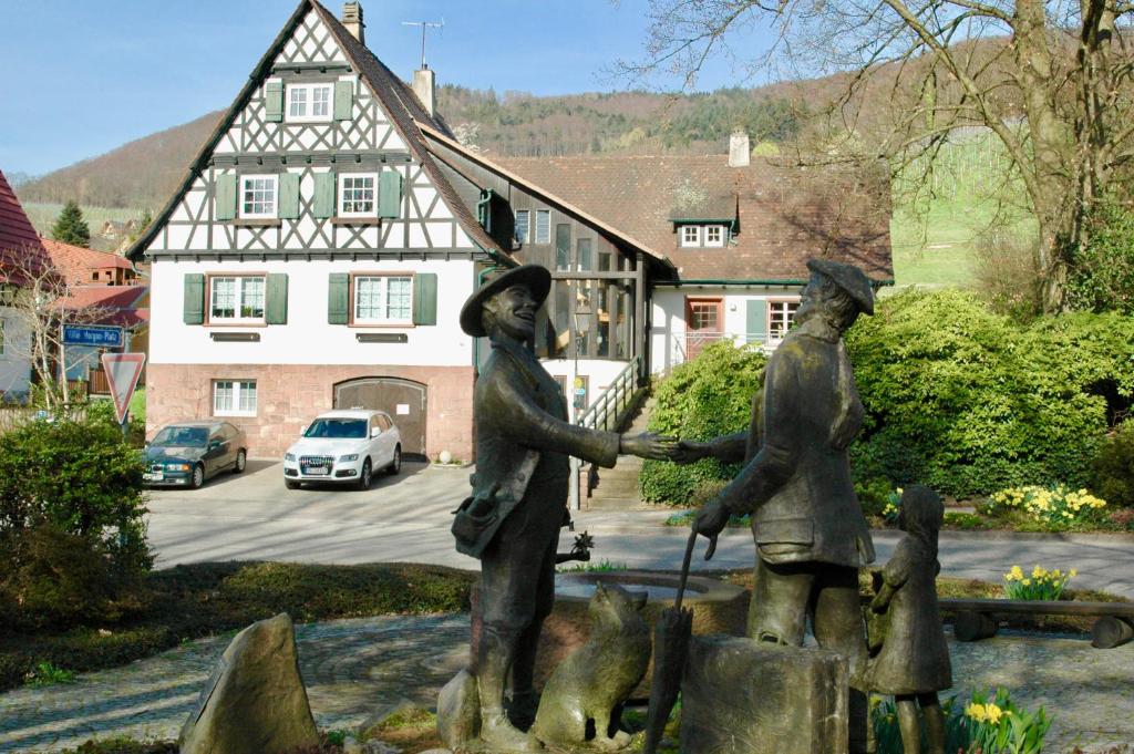 eine Statue von zwei Frauen, die vor einem Haus die Hände schütteln in der Unterkunft Ferienhaus Am Keschtebaum in Sasbachwalden