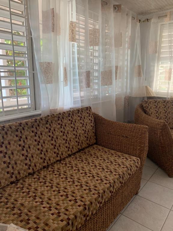 a couch sitting in front of a window with curtains at Beach Vue Barbados in Bridgetown