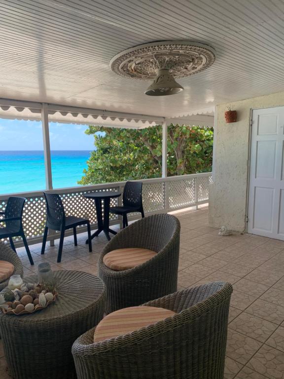 a patio with chairs and a table and the ocean at Beach Vue Barbados in Bridgetown