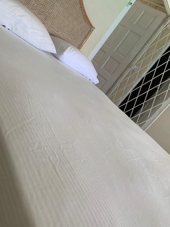 a close up of a bed with white sheets and pillows at Beach Vue Barbados in Bridgetown