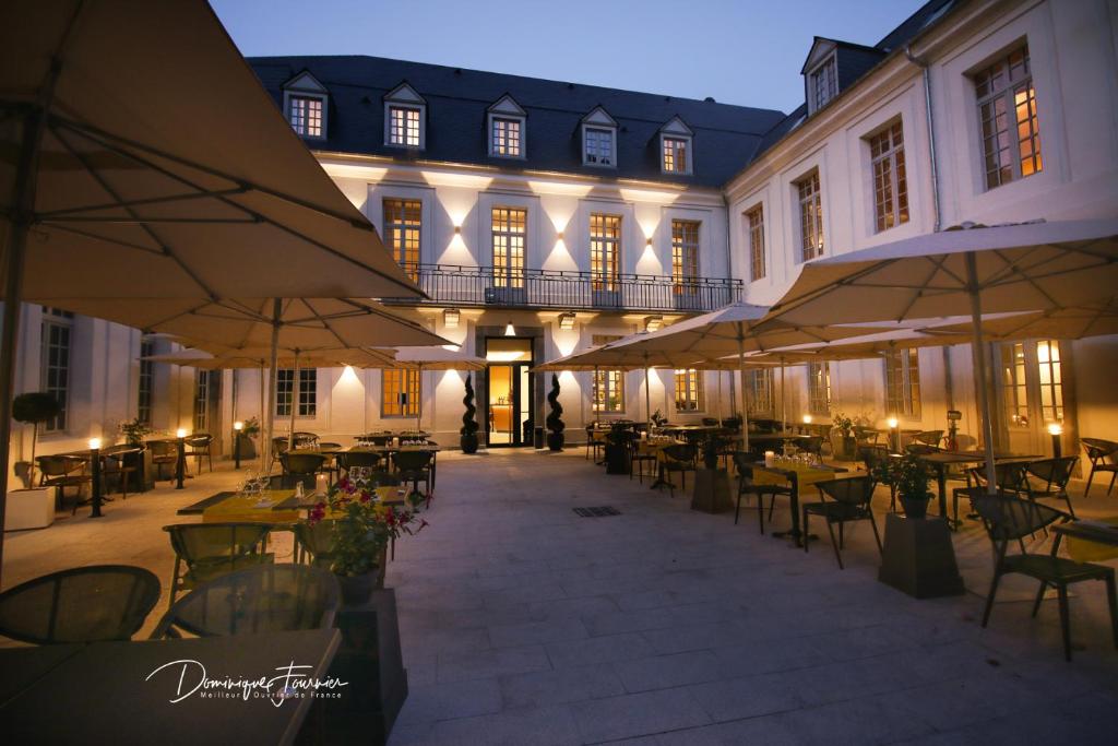 an empty courtyard with tables and chairs and umbrellas at LE CASTEL D'ALTI in Luchon