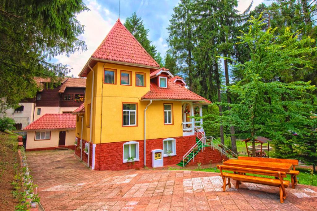 a large yellow house with a bench in front of it at Clermont Sinaia in Sinaia