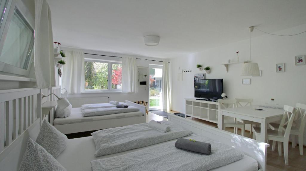 ein weißes Wohnzimmer mit 2 Betten und einem Tisch in der Unterkunft Innsbruck Apartment Nigler in Innsbruck
