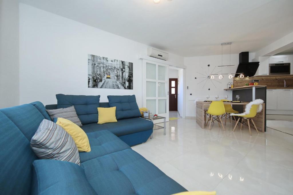 a living room with a blue couch and a kitchen at Villa Dalmatino in Pakoštane