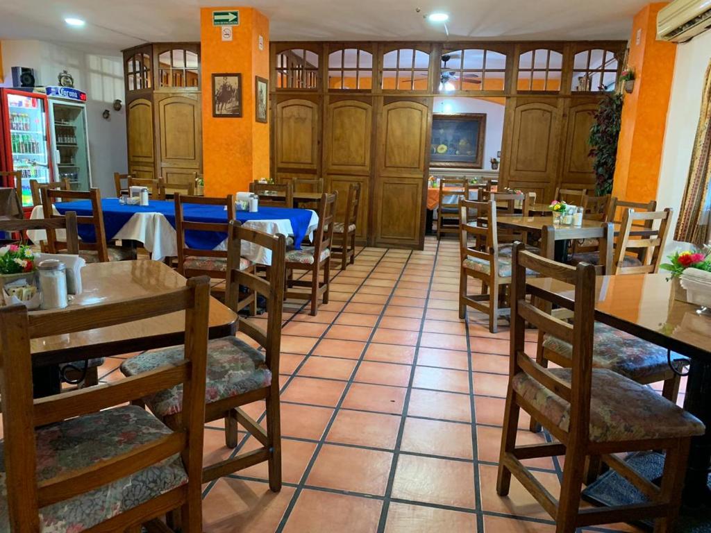 um restaurante com mesas e cadeiras de madeira numa sala em Hotel Las Fuentes em Los Mochis