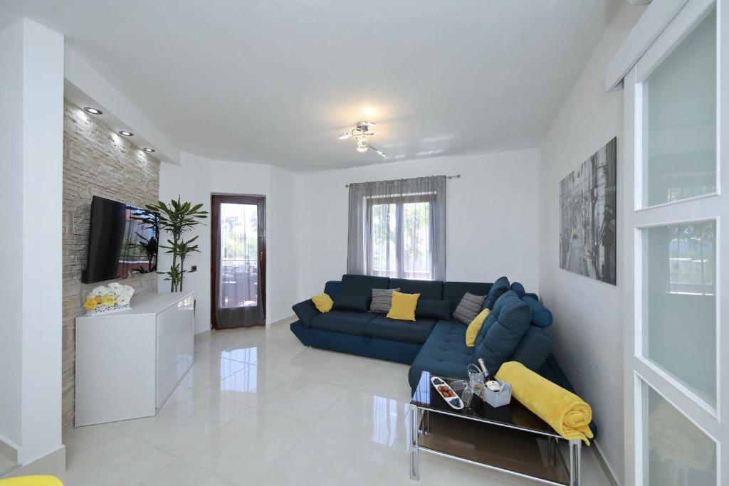a living room with a blue couch and a tv at Villa Dalmatino in Pakoštane