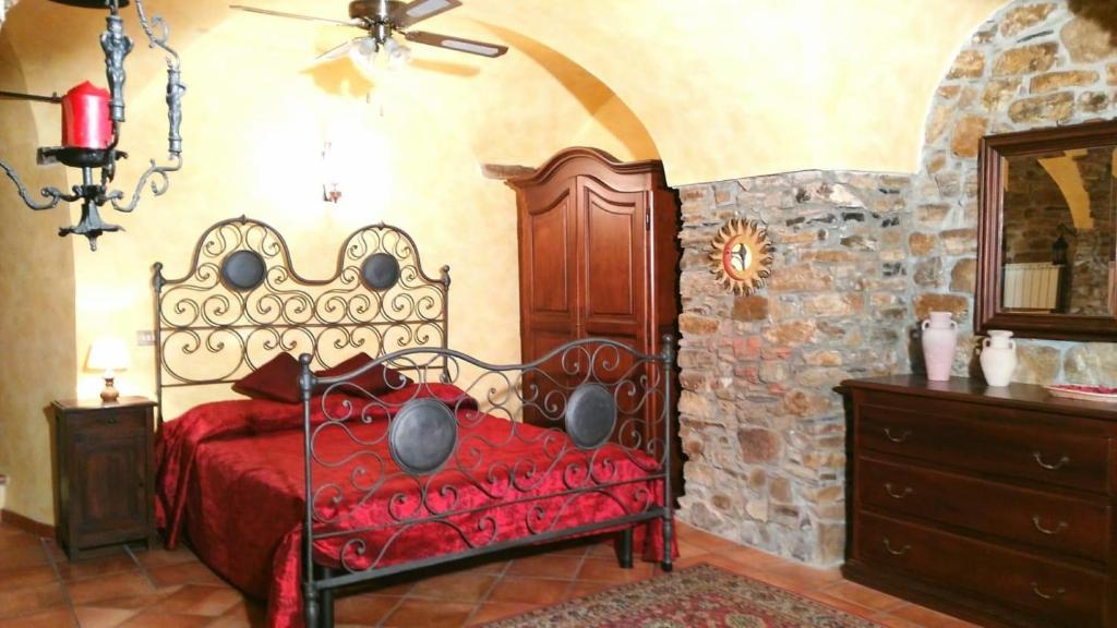 een slaapkamer met een rood bed en een stenen muur bij ''SAPORE DI LIGURIA'' Sole Mare Quiete in Terzorio