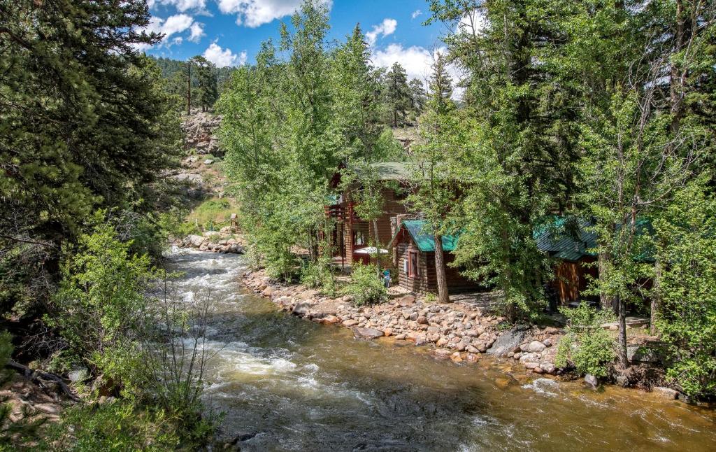 um rio ao lado de uma cabana na floresta em Swiftcurrent Lodge em Estes Park