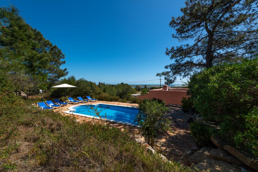a swimming pool with chairs and an umbrella at Casa Rosa in Luz de Tavira
