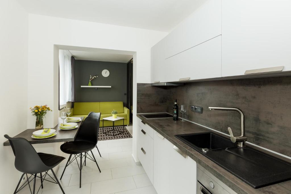 a kitchen with a sink and a table with chairs at Apartmány Stožec - Stela Premium in Stožec