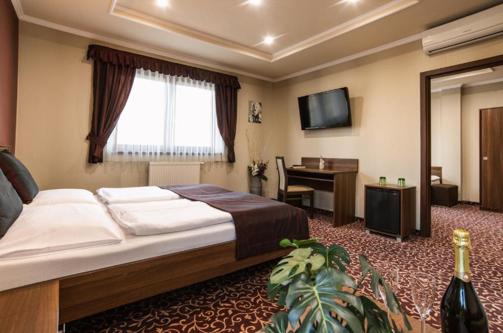 a bedroom with a bed and a desk and a television at Corvin Pension and Restaurant in Veľký Meder