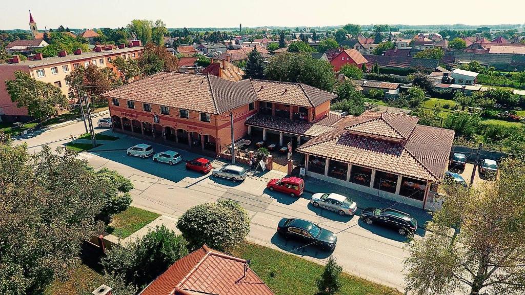 un gran edificio con coches estacionados en un estacionamiento en Corvin Pension and Restaurant, en Veľký Meder