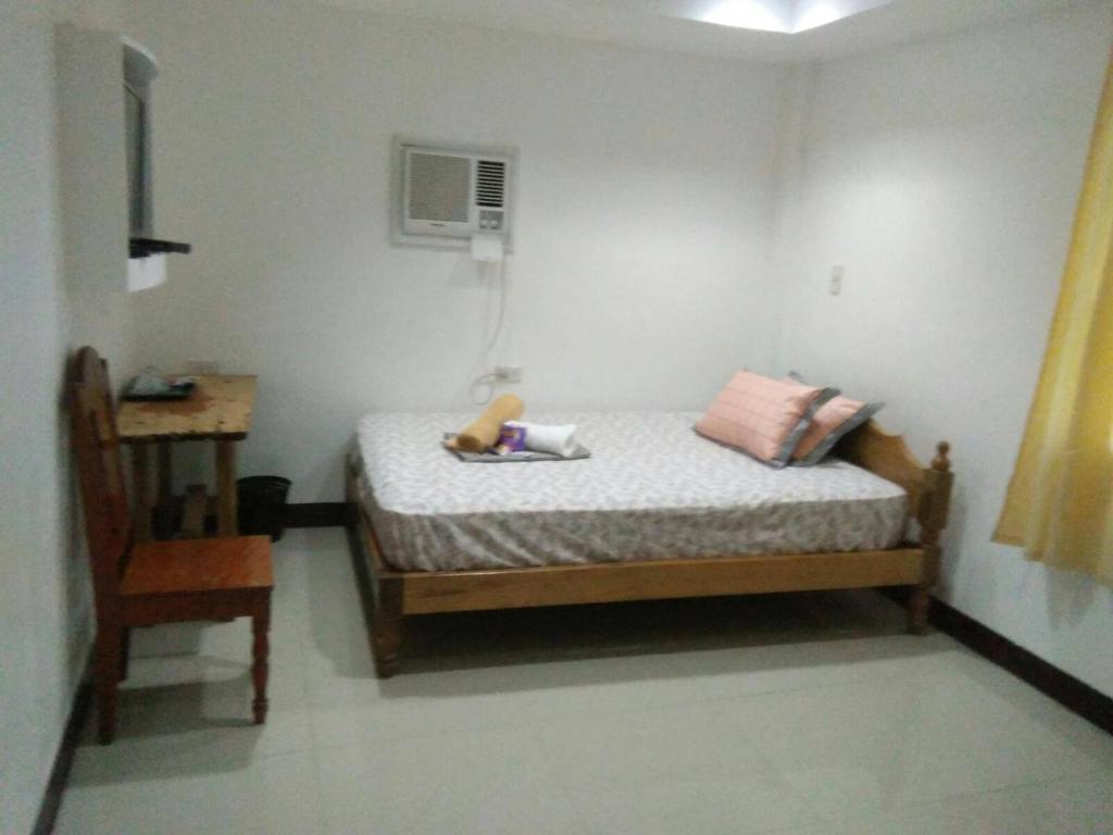 ein kleines Schlafzimmer mit einem Bett und einem Stuhl in der Unterkunft Andreas Homestay in Del Carmen