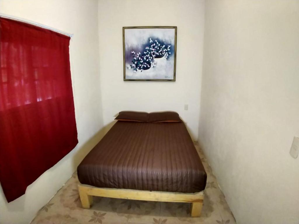 - un petit lit dans une chambre dotée d'un rideau rouge dans l'établissement Departamento a 5 minutos de playa Mismaloya, Puerto Vallarta, à Puerto Vallarta