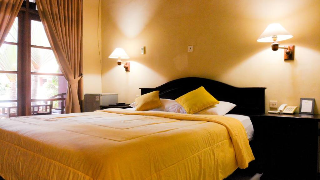 a bedroom with a large bed with yellow sheets at Masainn Hotel Kuta in Kuta