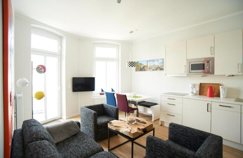ein Wohnzimmer mit 2 Sofas und einer Küche in der Unterkunft Apartment Eisberg 3 mit schöner Balkonterrasse in Norderney
