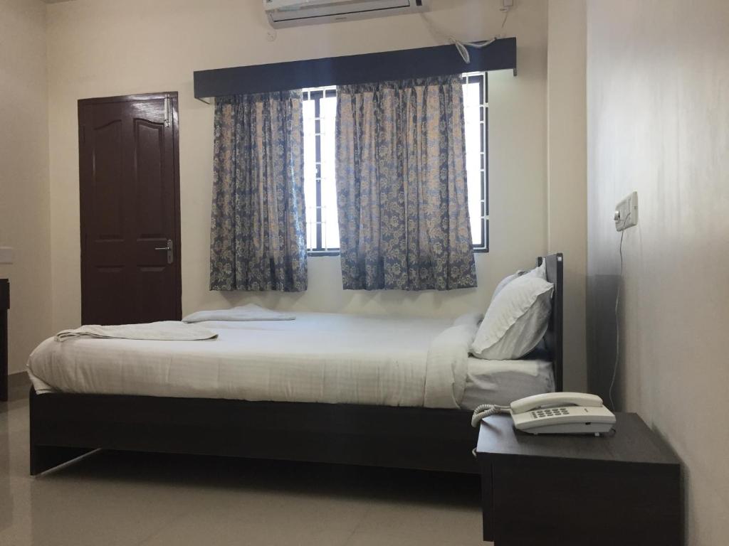 um quarto com uma cama e um telefone ao lado de uma janela em Sun Shine em Chennai