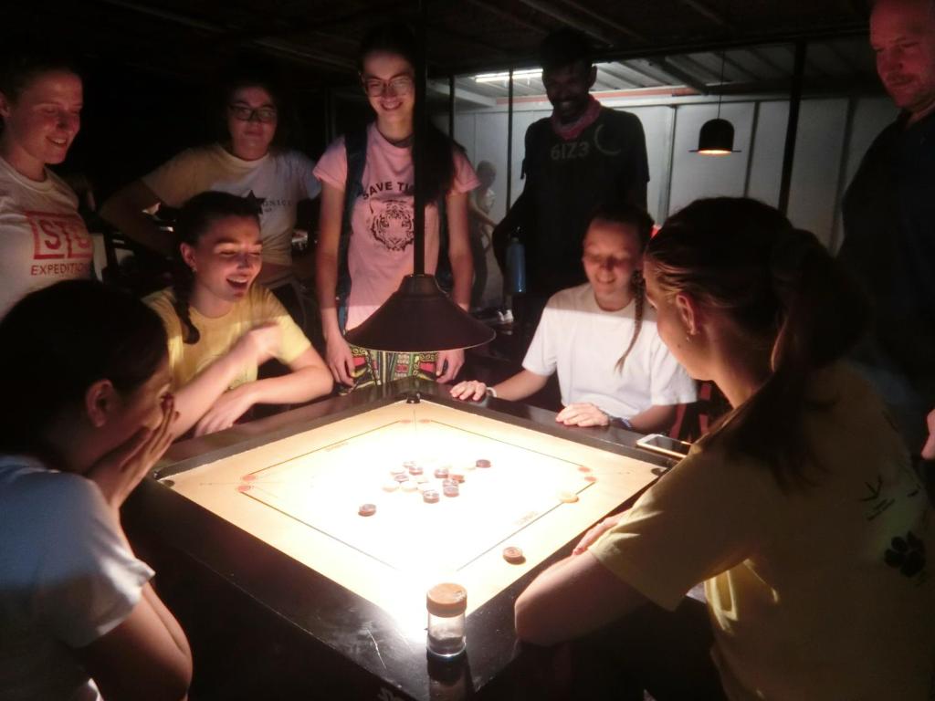 Eine Gruppe von Menschen steht um einen Tisch mit einem Spiel. in der Unterkunft Kochill - Relax & Stay - in Kochi