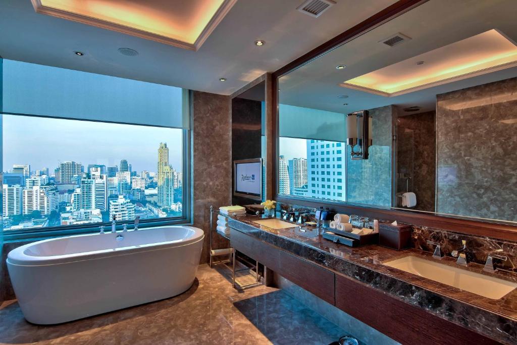 バンコクにあるRadisson Blu Plaza Bangkokのバスルーム(バスタブ、シンク2台付)、大きな窓が備わります。