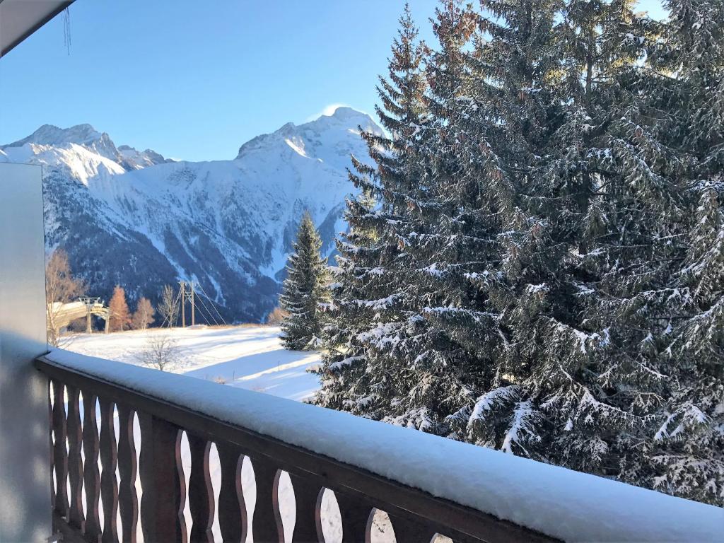 a snow covered tree on a balcony with snow covered mountains at Boost Your Immo Les Deux Alpes 174 / Le Midi in Les Deux Alpes