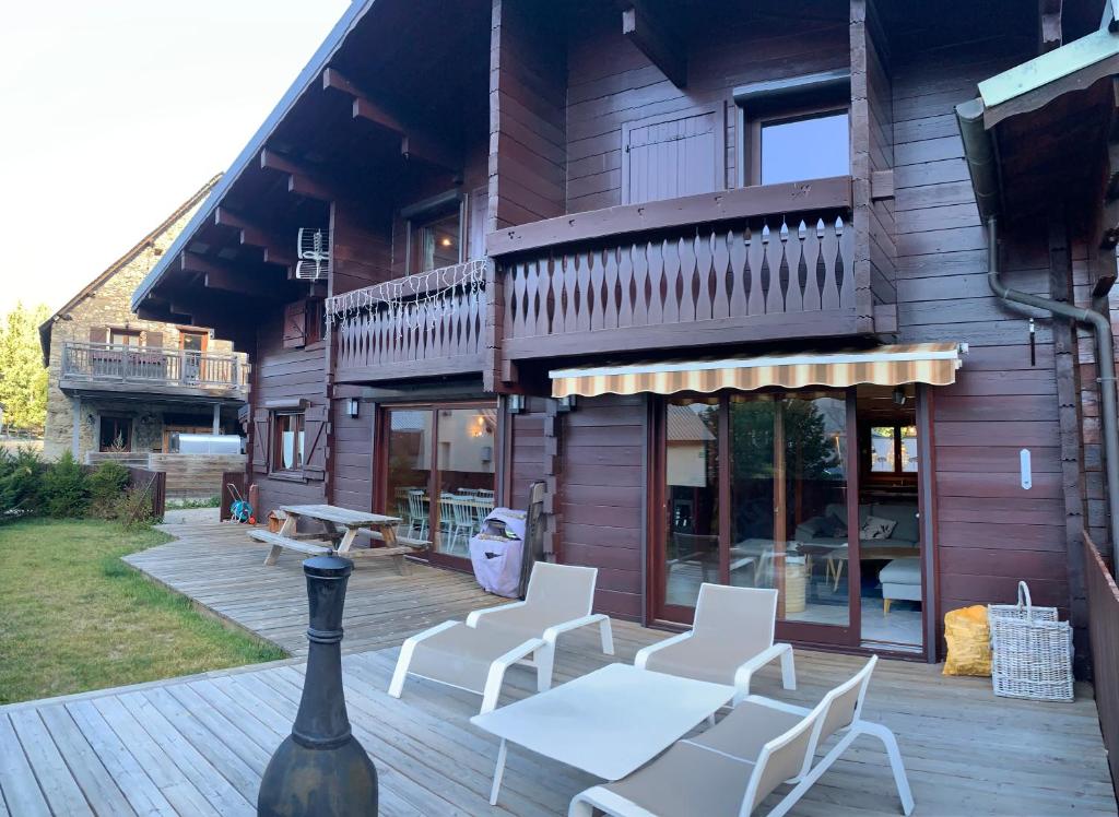 a wooden deck with white chairs and a building at Boost Your Immo Les Deux Alpes Chalet Gaspard 184 in Les Deux Alpes