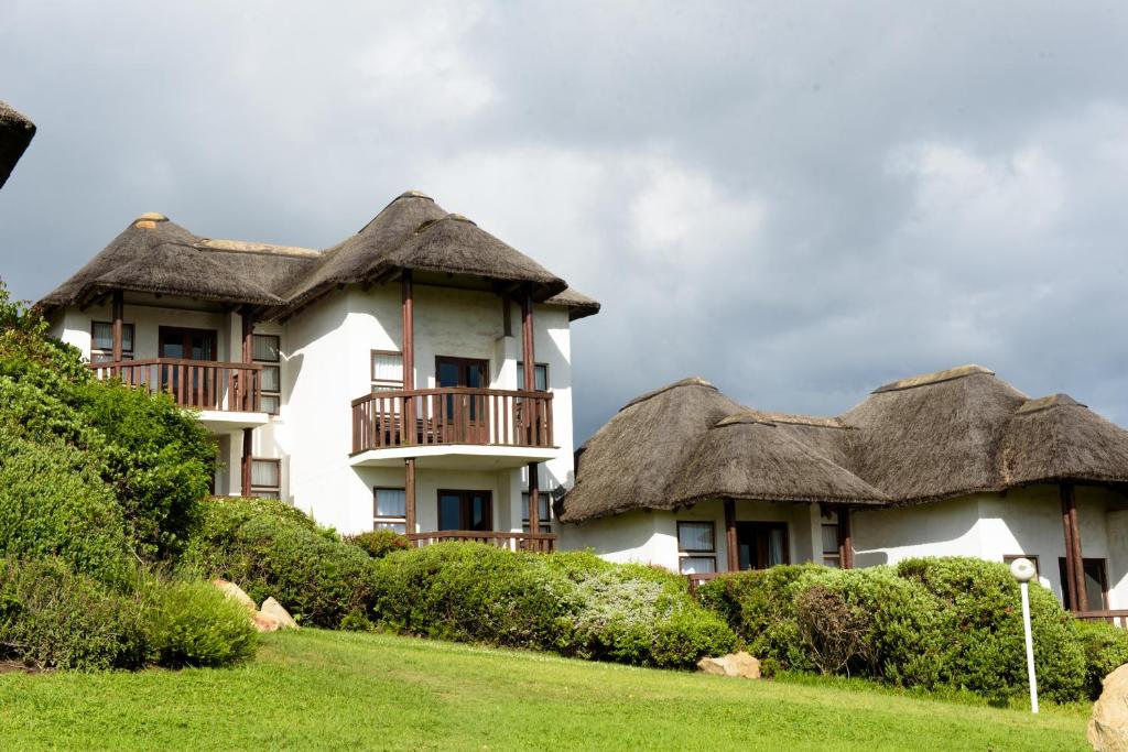 a building with thatched roofs on top of a field at Whalesong Hotel & Spa in Plettenberg Bay
