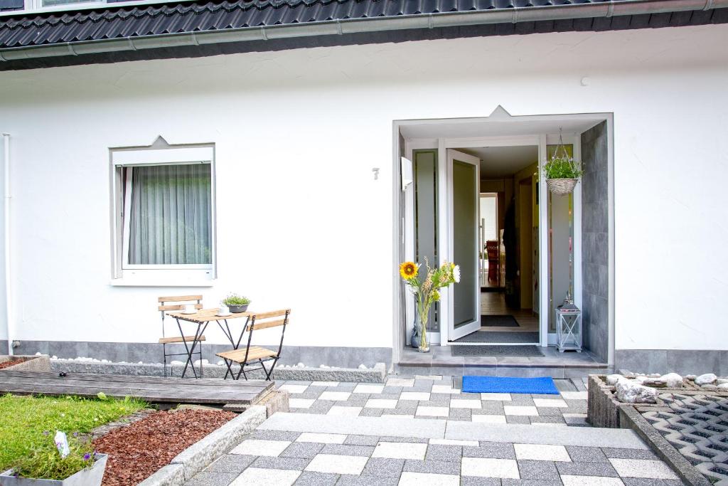 un porche delantero de una casa blanca con mesa y sillas en Pension zum Rothaarsteig Selbstversorgerhaus, en Netphen