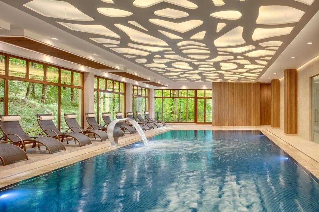 a pool in a hotel with chairs and a ceiling at Ensana Svoboda in Mariánské Lázně