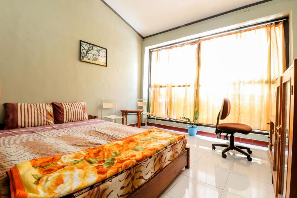 a bedroom with a bed and a chair and a window at Nabhan Homestay in Kalirejo