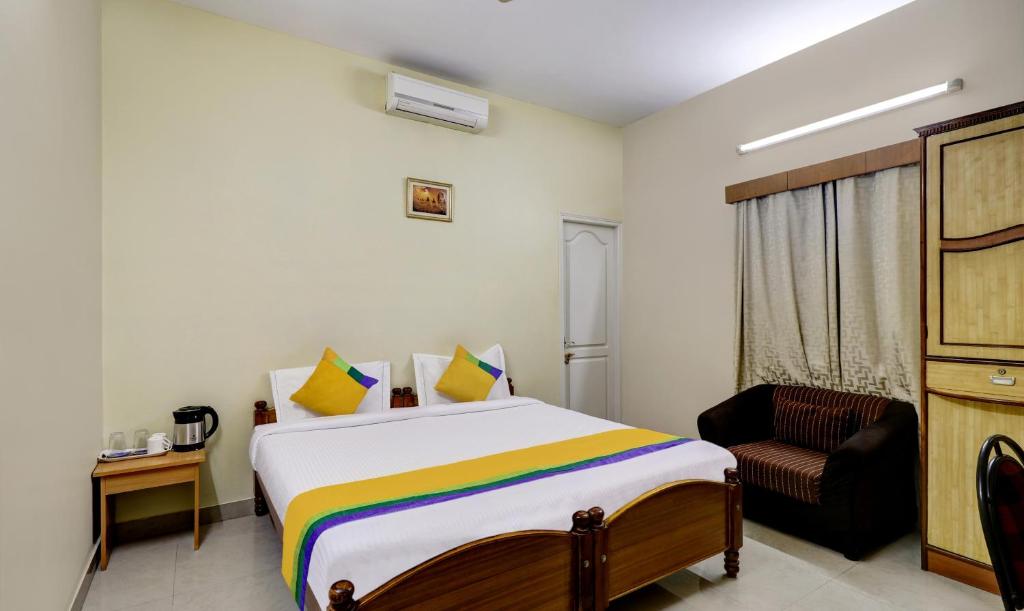 1 dormitorio con 1 cama y 1 silla en Itsy By Treebo - Shree Comforts, en Bangalore
