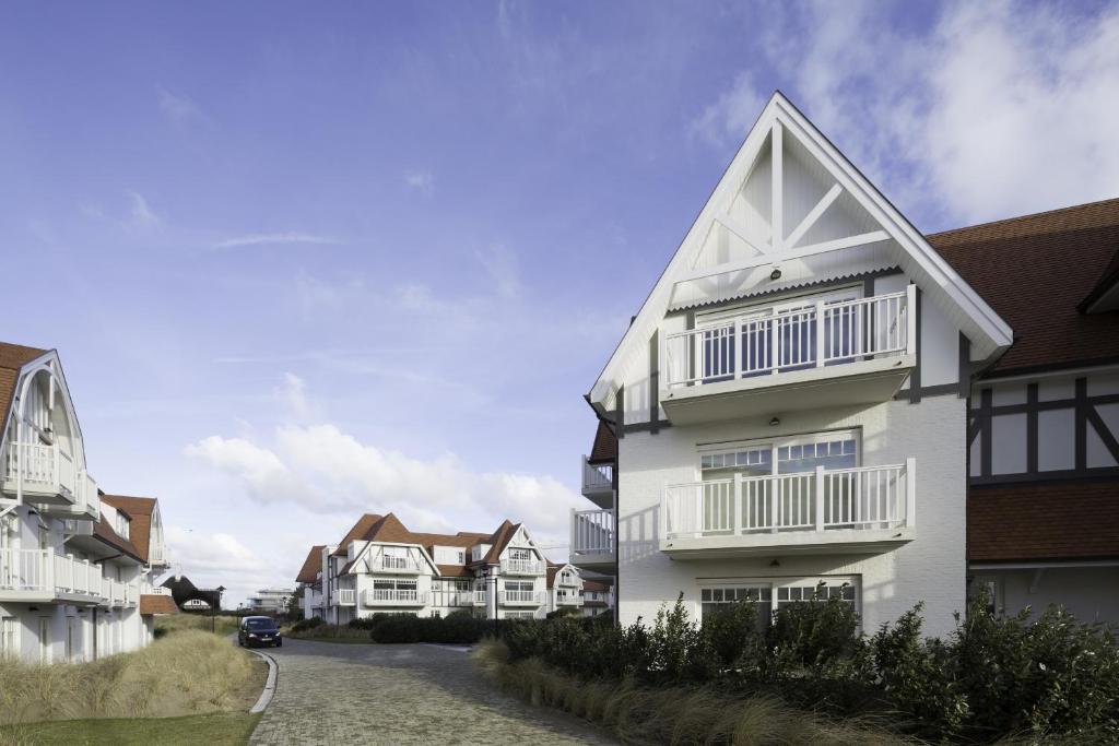 a white house with balconies on the side of a street at EastDune in Oostduinkerke