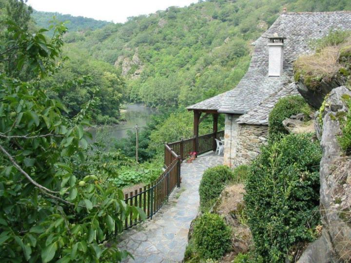 ein Steinhaus mit einem Gehweg neben einem Fluss in der Unterkunft Le Four in Vieillevie