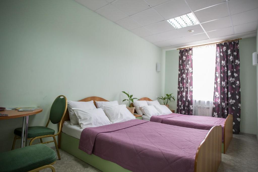 two beds in a room with a table and chairs at Hotel Stara Zagora in Samara