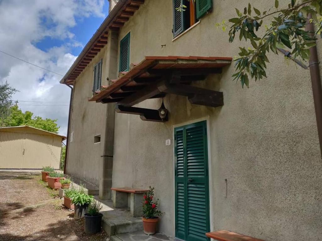 un edificio con una puerta verde y un porche en Il Rusticano, en Chianni