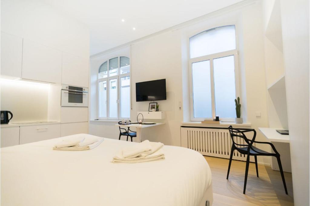 a white room with two beds and a kitchen at Smartflats - Luxembourg in Luxembourg