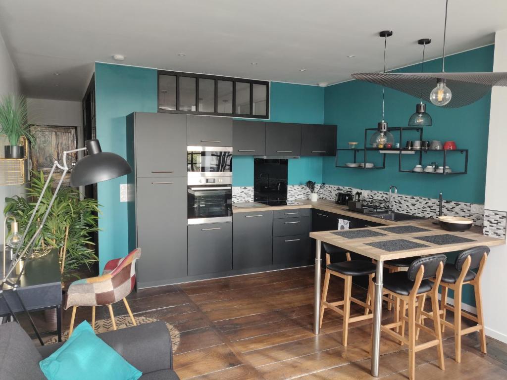 - une cuisine avec des murs bleus, une table et des chaises dans l'établissement Appmt Cosy 2 pièces - Haut Standing, à Bayonne