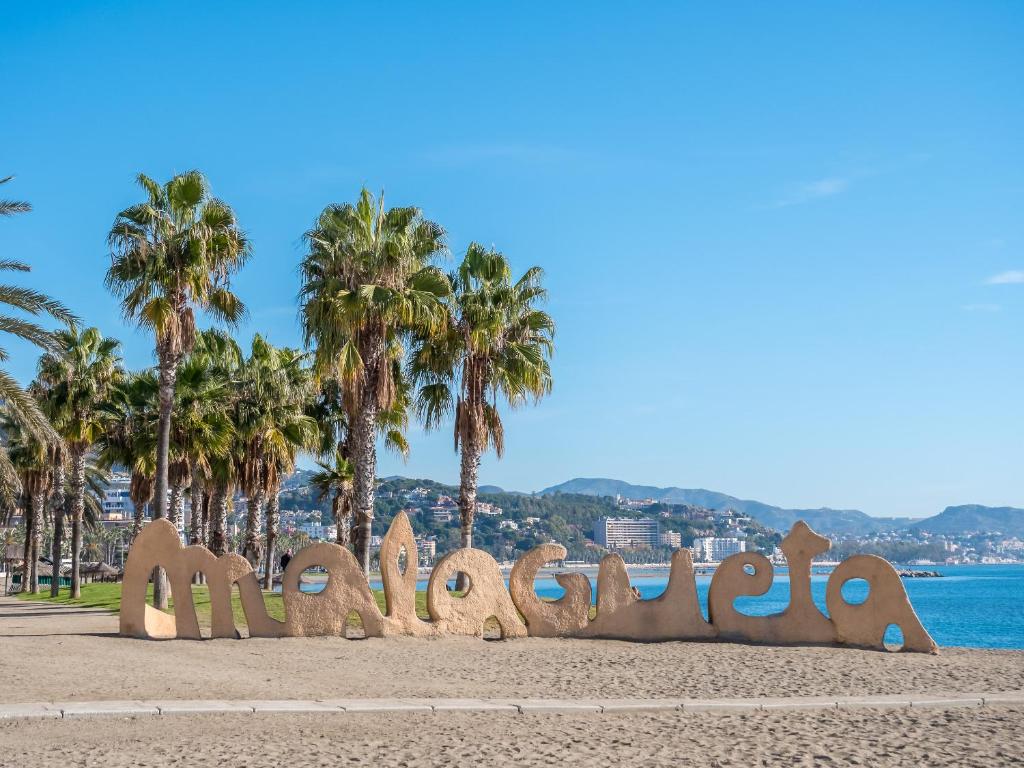 un cartel en una playa con palmeras en el fondo en PREMIUM BEACH DESIGN - La Malagueta en Málaga