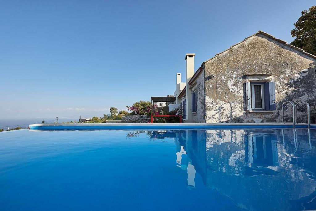 a house and a swimming pool with blue water at Philyra Farmhouse in Epáno Kefalás