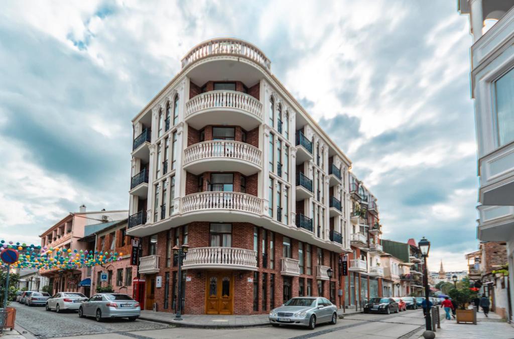 a tall brick building with balconies on a city street at Hotel London in Batumi