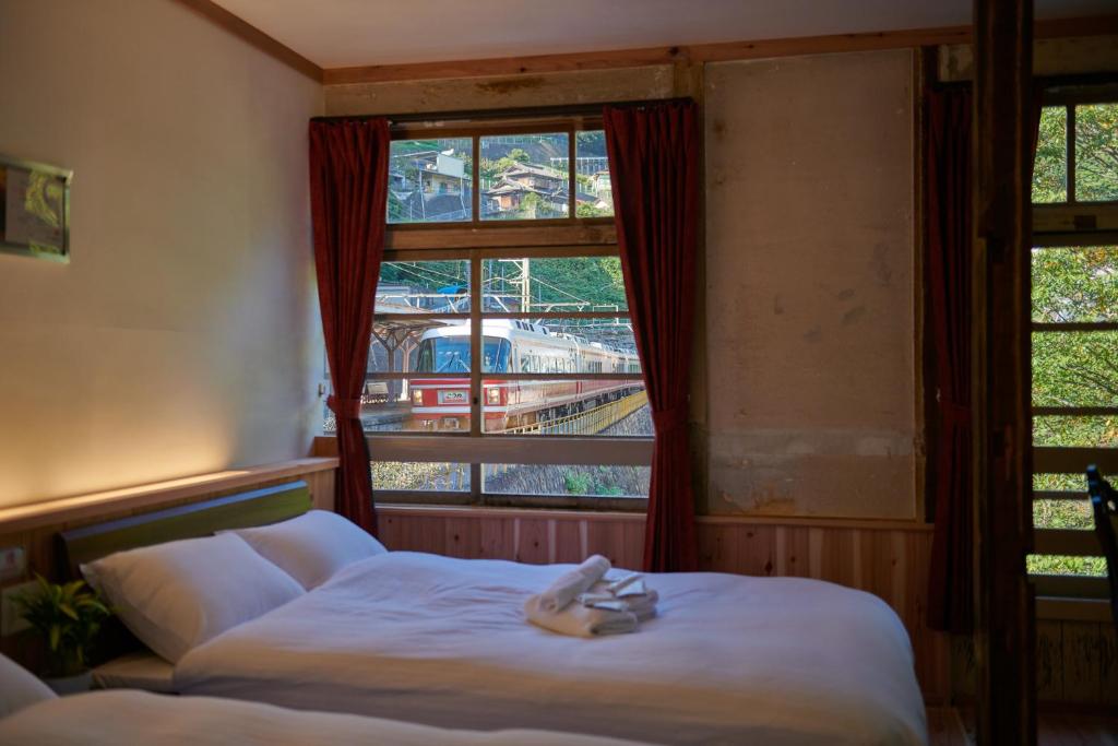 a bedroom with a bed and a train through a window at The Railway Hotel Koyasan Pilgrimage Railway - Station Inn - Self Check-in Only in Kudoyama