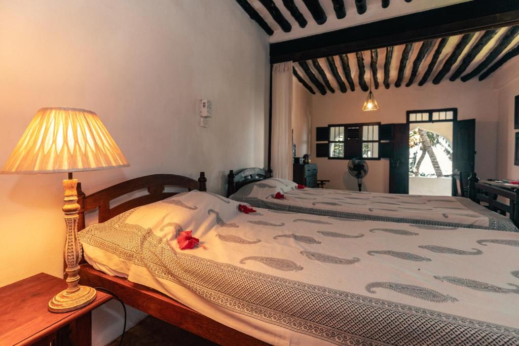 a bedroom with a bed with a lamp on a table at Kijani Hotel in Lamu
