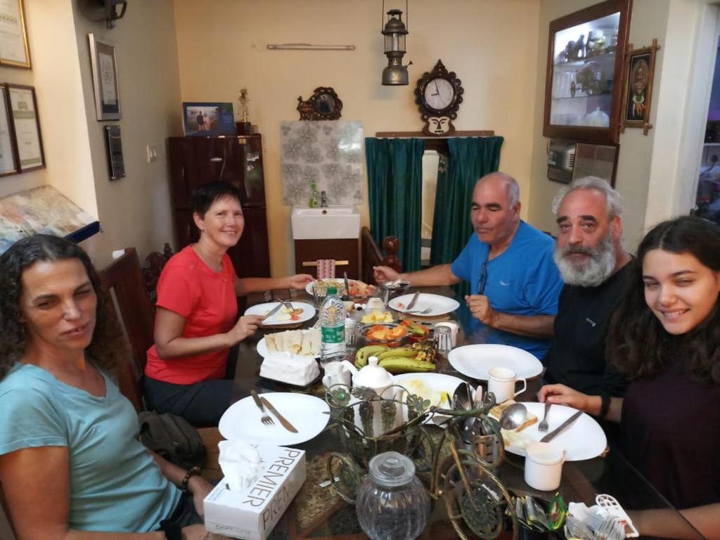 un grupo de personas sentadas alrededor de una mesa comiendo comida en Heavenly Homestay, en Kochi