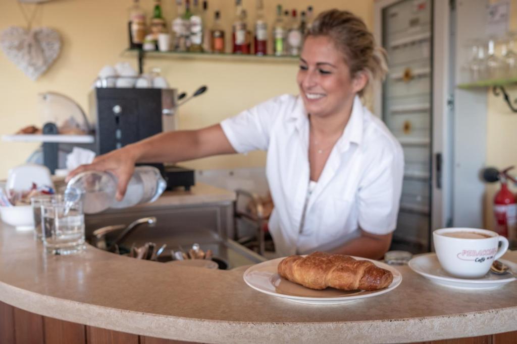 a woman standing in a kitchen with a plate of bread at Residenza Principina in Principina Terra