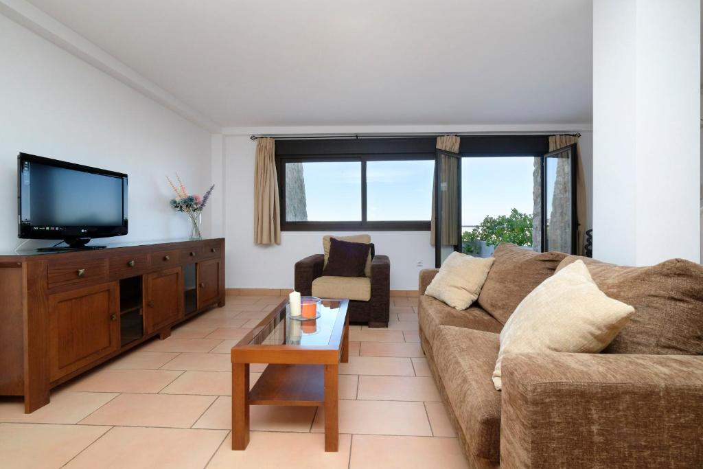 Una sala de estar con un sofá y un televisor. en Los Castillarejos Apartamentos Rurales, en Luque